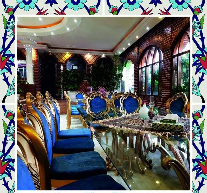 رستوران باغ طهرون: دکوراسیون داخلی لوکس با میز شیشه‌ای بزرگ، صندلی‌های سلطنتی آبی و دیوارهای آجری با پنجره‌های قوسی رو به باغی سرسبز.