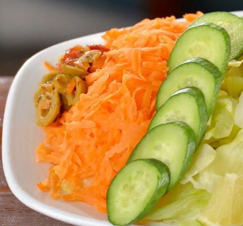 سالاد سبزیجات تازه و رنگارنگ رستوران باغ طهرون: هویج رنده، خیار اسلایس، زیتون و کاهو. غذایی سالم و لذت‌بخش در محیطی دلنشین.