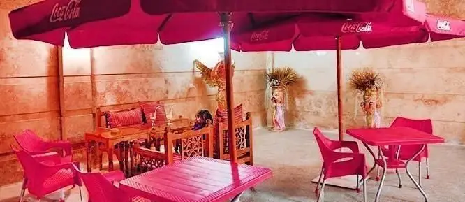 فضای باز دلنشین رستوران عربی پالمیرا با میز و صندلی‌های شیک سرخابی، سایبان کوکاکولا و دکوراسیون سنتی خاورمیانه‌ای.