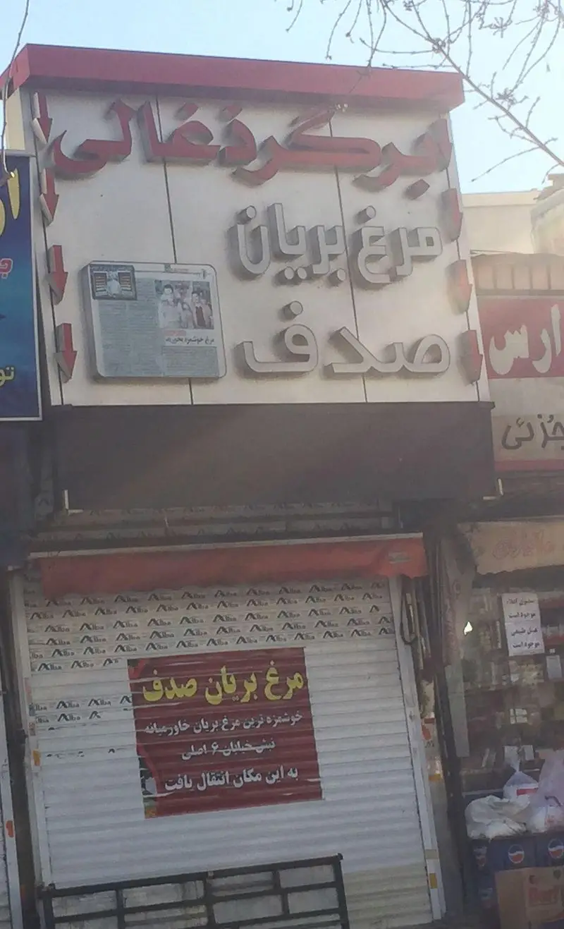 تصویری از نمای بیرونی مغازه مرغ بریان صدف، با تابلوی مرغ ذغالی، پیام انتقال به این مکان و تبلیغ خوشمزه‌ترین مرغ خاورمیانه.