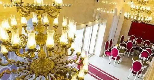 دکوراسیون داخلی لوکس رستوران ایرانی دهکده با لوسترهای طلایی و زیبا، چیدمان چشم‌نواز میز و صندلی‌های قرمز و فضایی مجلل برای مهمانی‌ها.