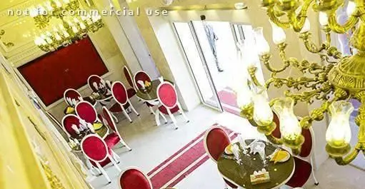 فضای داخلی شیک و مجلل رستوران ایرانی دهکده؛ میز و صندلی‌های قرمز کلاسیک، لوستر طلایی، دیوار قرمز و دکوراسیون چشم‌نواز.