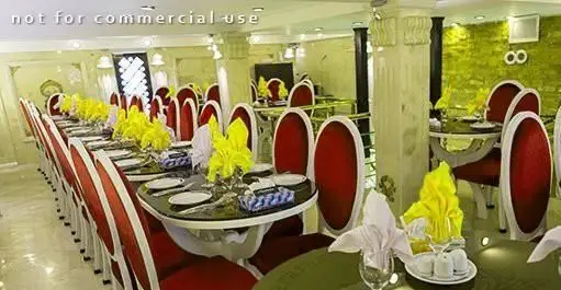 فضای داخلی رستوران ایرانی دهکده با چیدمان میز و صندلی‌های شیک قرمز و سفید، دکوراسیون مدرن و میزهای آماده پذیرایی از مشتریان.