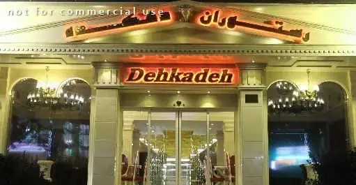 نمای بیرونی شب رستوران ایرانی دهکده با نورپردازی گرم و ورودی شیک، مناسب برای تجربه طعم اصیل غذای ایرانی.