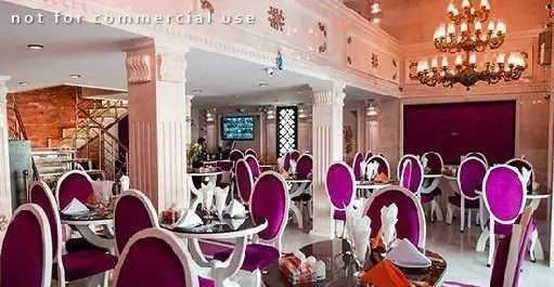 دکوراسیون داخلی شیک و مدرن رستوران ایرانی دهکده با میز و صندلی‌های مجلل بنفش و لوسترهای زیبا. محیطی دلنشین برای صرف غذای اصیل ایرانی.