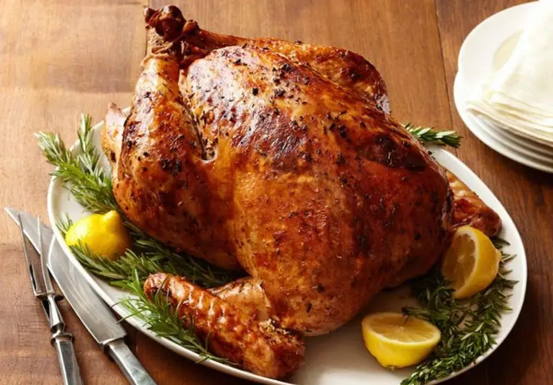 بوقلمون کامل بریان شده و طلایی با رزماری و لیمو، آماده سرو. غذایی دلپذیر از فست فود کره برای مهمانی و مراسم.