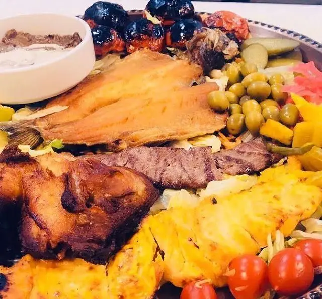 سفره خانه سنتی ماندگار: سینی مجلل غذاهای اصیل ایرانی شامل ماهی کامل، انواع کباب، جوجه و مخلفات رنگارنگ.