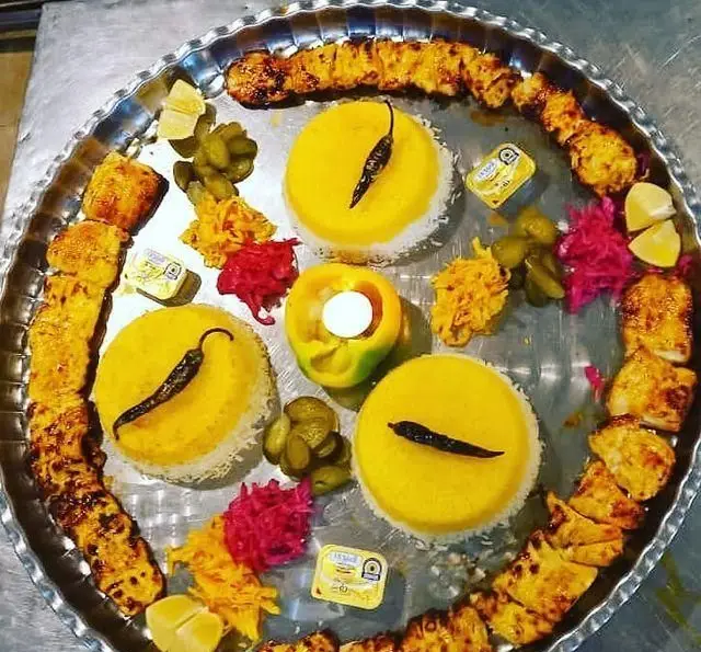 کباب جوجه و چلو زعفرانی در سفره خانه سنتی ماندگار. سینی غذای مجلل با مخلفات، لیمو، کره و دیزاین خاص. غذای ایرانی اصیل و لذیذ.