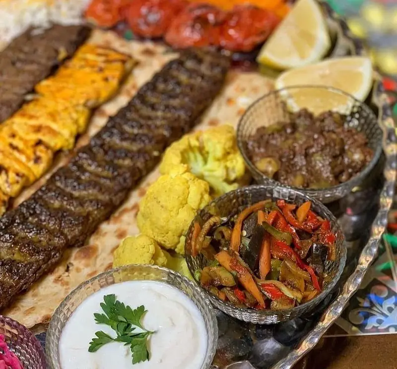 سینی جذاب غذای ایرانی سفره خانه سنتی ماندگار شامل کباب کوبیده، جوجه، ترشی، ماست و مخلفات خوشمزه.