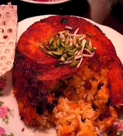 ته چین مجلسی پلو زعفرانی زرشک‌دار، غذای سنتی رستوران ایرانی خونه با ته دیگ طلایی و مغز پسته و بادام.