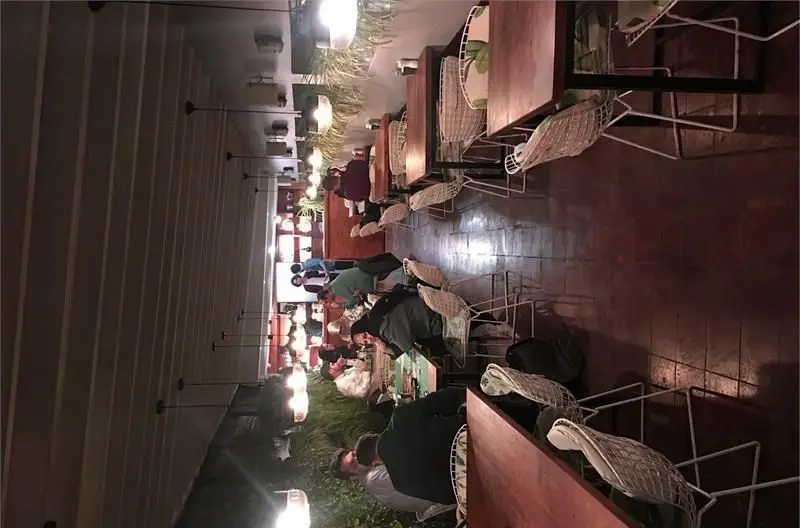 تصویر دلنشین از فضای داخلی رستوران ایرانی خونه در شب، شامل مشتریان، میزهای چوبی و صندلی‌های مدرن با نورپردازی گرم.