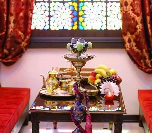 کافی شاپ موروکو، فضایی سنتی و دلنشین با قلیان، سینی چای طلایی و میوه‌های تازه، در کنار پنجره‌های شیشه‌ای رنگی.