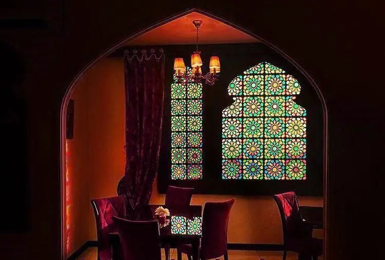 نمایی از فضای داخلی جذاب کافی شاپ موروکو با پنجره‌های رنگی طرح‌دار مراکشی، لوستر آویزان و مبلمان دنج قرمز