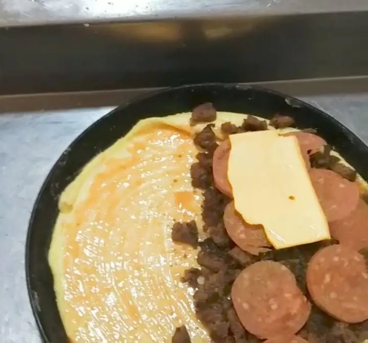 پیتزا هات شهرک غرب: فرآیند آماده سازی پیتزای خوشمزه و تازه با خمیر، سس، گوشت چرخ کرده، پپرونی و پنیر قبل از پخت.