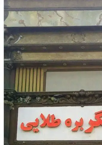 تابلو سردر کسب و کار قصر جگر بره طلایی با حروف برجسته قرمز رنگ در نمای تزئین شده مغازه، نشان‌دهنده یک رستوران ایرانی.