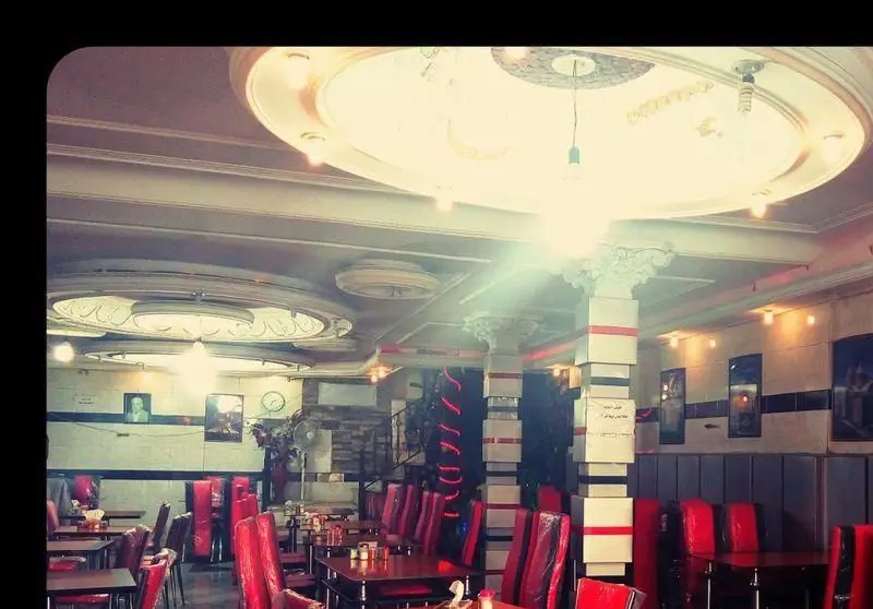 فضای داخلی رستوران قصر جگر بره طلایی با میز و صندلی‌های قرمز و دکوراسیون شیک و نورپردازی جذاب برای یک تجربه غذایی دلنشین.