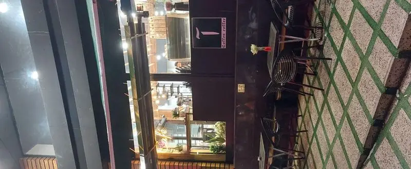 کافه آ با فضای باز دلنشین و دکوراسیون مدرن در شب، میز و صندلی‌های راحت و گل‌های تازه برای تجربه‌ای لذت‌بخش.