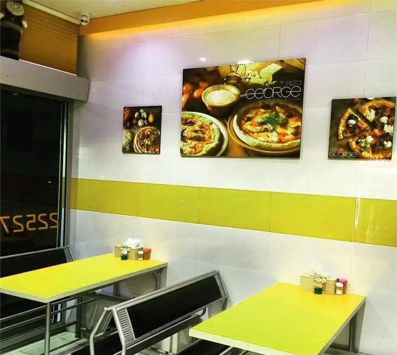 محیط داخلی پیتزا فروشی ژرژ با دکوراسیون مدرن و میزهای زرد، پوسترهای جذاب پیتزا و فضایی مناسب برای تجربه طعم بی‌نظیر پیتزا ژرژ.