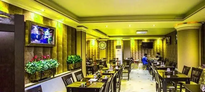 فضای داخلی دلباز و مدرن فست فود شاپرک با میز و صندلی‌های چوبی، دکوراسیون شیک و تلویزیون‌های دیواری، محیطی عالی برای مشتریان.