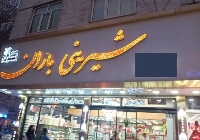نمای بیرونی شیرینی فروشی باران با تابلوی درخشان، ویترین پر از شیرینی و مشتریان در حال خرید. یک کسب و کار جذاب شیرینی پزی.