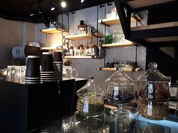 نمای داخلی شیک کافه ایوان؛ پیشخوان مجهز به انواع نوشیدنی، شیشه‌های چای و دمنوش، قفسه‌های چوبی، و نورپردازی خاص؛ فضایی دلپذیر.