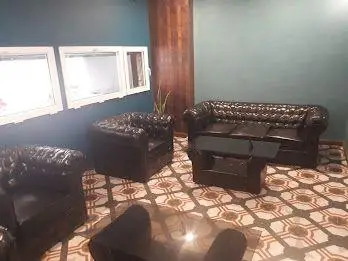 دکوراسیون داخلی شیک کافه ایوان با مبلمان راحتی چرمی تیره، دیوارهای فیروزه‌ای و کفپوش زیبا. محیطی دلنشین برای مشتریان.