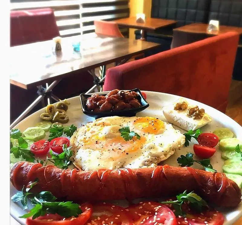 لذت صبحانه ای رویایی در کافه لند: بشقابی رنگارنگ با سوسیس گریل، تخم مرغ، پنیر، زیتون و سالاد تازه. تجربه ای دلپذیر!