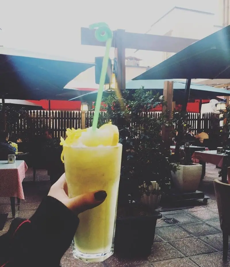 نوشیدنی خنک و لذیذ در فضای باز کافه لند: اسموتی میوه ای تازه با نی فانتزی، انتخابی عالی برای روزهای گرم تابستان و کافه گردی.