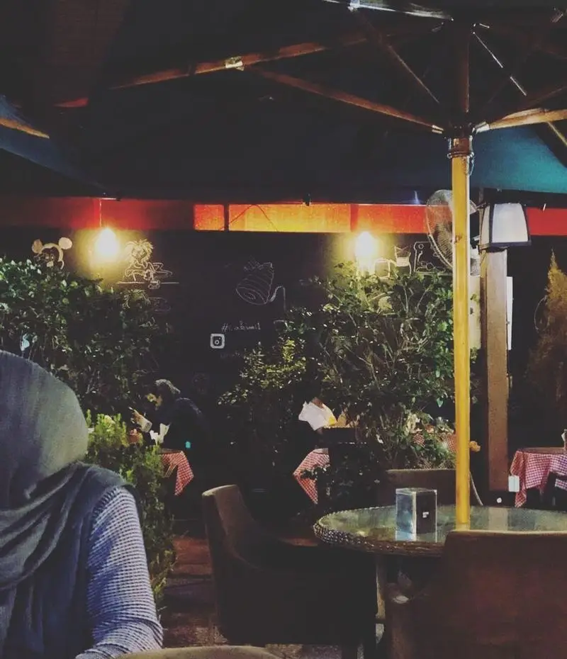 کافه لند در شب: محیطی دلنشین و دنج با نورپردازی گرم، نقاشی‌های دیواری خلاقانه، میز و صندلی راحت و مشتریان. تجربه نوشیدنی عالی.