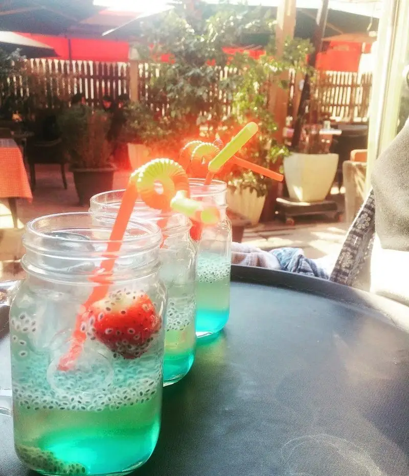 سه نوشیدنی خنک و تابستانی کافه لند با بذر ریحان و توت فرنگی در فضای باز. مناسب برای روزهای گرم و لذت بردن از منوی متنوع.