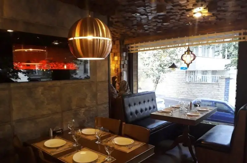 فضای داخلی دنج و مدرن رستوران پیتزا پاستا استیک با میزهای چوبی، صندلی‌های راحتی و نورپردازی زیبا، آماده پذیرایی از مشتریان.