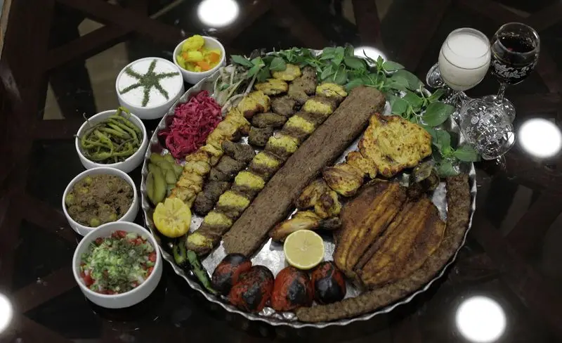 سینی کباب بزرگ ایرانی شامل کوبیده، جوجه، ماهی و چنجه، با ماست و سالاد شیرازی در رستوران سنتی شهر آفتاب، غذای سنتی لذیذ.
