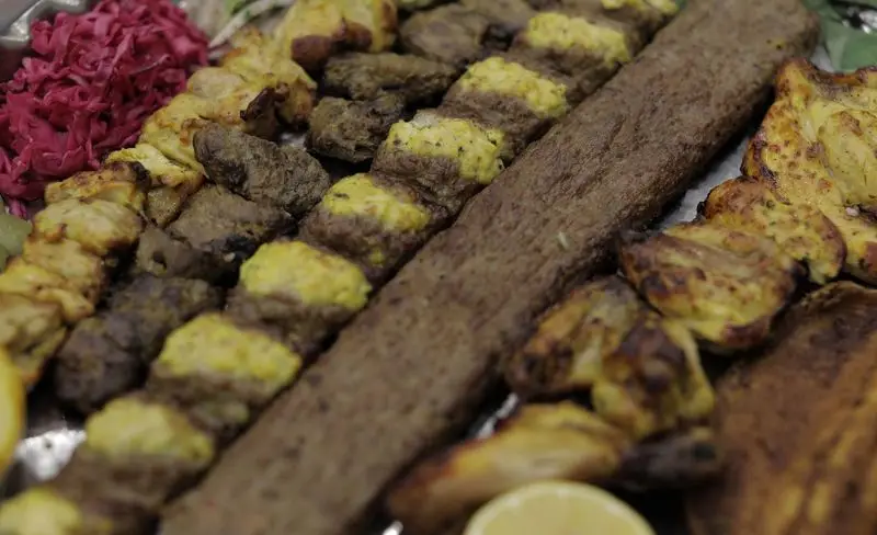 یک سینی چیدمان شده از انواع کباب‌های لذیذ ایرانی شامل کوبیده، جوجه کباب و کباب گوشت، با ترشی و لیمو تازه در رستوران سنتی شهر آفتاب.