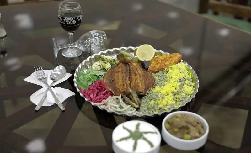 ماهی سرخ شده با سبزی پلو و مخلفات لذیذ در رستوران سنتی شهر آفتاب. تجربه‌ای بی‌نظیر از غذای اصیل ایرانی.