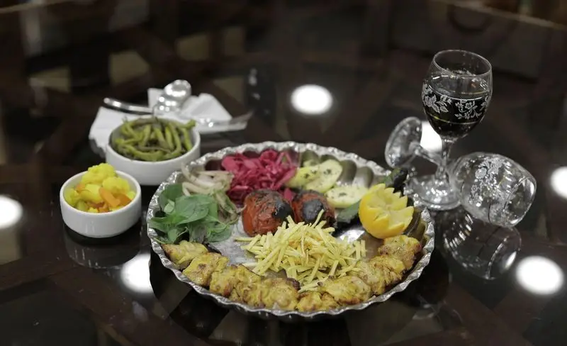 میز غذای لذیذ در رستوران سنتی شهر آفتاب: کباب جوجه، گوجه کبابی، سیب زمینی، ترشی و سبزیجات تازه. تجربه‌ای دلنشین از غذای اصیل ایرانی.