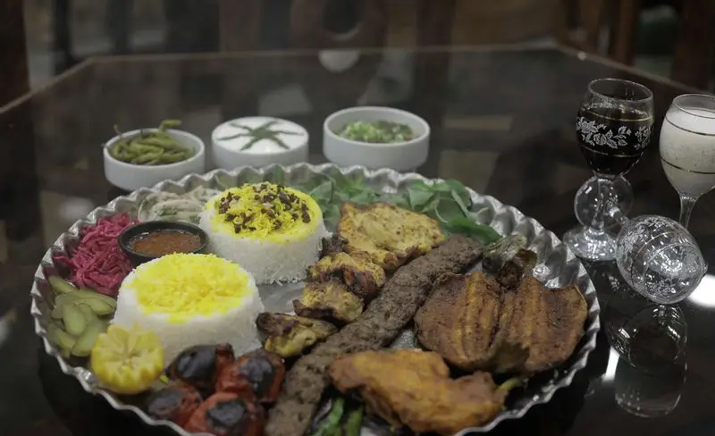 سینی مجلل غذاهای سنتی ایرانی در رستوران شهر آفتاب: انواع کباب، برنج زعفرانی، ماست، ترشی و سبزیجات تازه.