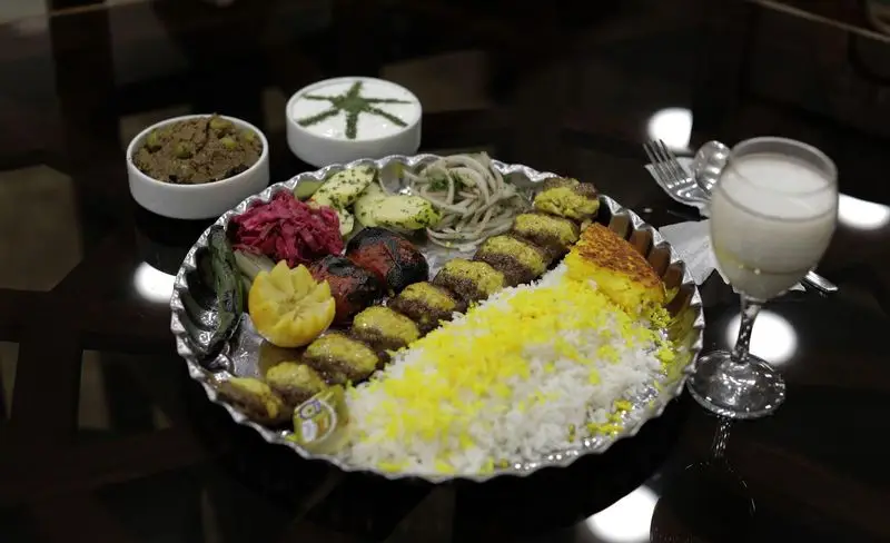 غذای سنتی ایرانی، چلو کباب کوبیده خوشمزه با ته‌دیگ زعفرانی، قورمه سبزی، ماست و خیار و دوغ در رستوران سنتی شهر آفتاب.