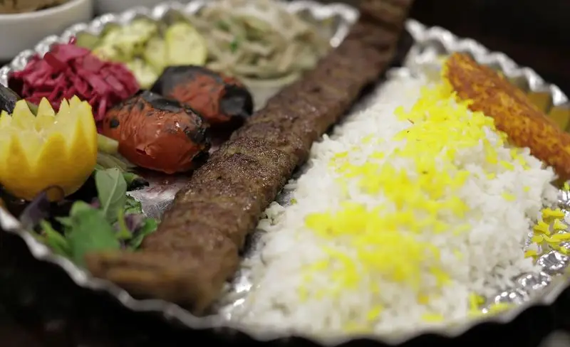 کباب کوبیده لذیذ با چلو زعفرانی، گوجه کبابی و تزیینات زیبا در رستوران سنتی شهر آفتاب. بهترین غذای ایرانی باکیفیت و اصیل.