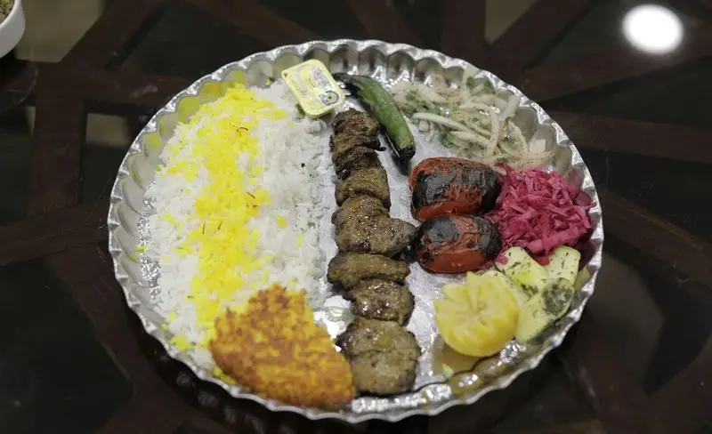چلوکباب لذیذ با برنج زعفرانی، گوجه کبابی، ترشی، پیاز، سیب زمینی و لیمو، سرو شده در رستوران سنتی شهر آفتاب.