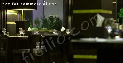 فضای داخلی رستوران فرنگی رمان، با دکوراسیون شیک و نورپردازی ملایم. میزهای چیده شده با لیوان‌های آماده برای تجربه یک وعده غذایی فراموش‌نشدنی.