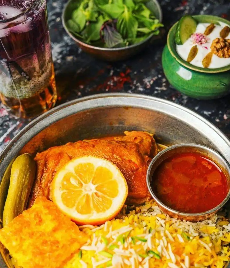 سفره رنگین غذای اصیل ایرانی رستوران پیاله: چلو مرغ زعفرانی، ته دیگ، ماست و خیار، سبزی خوردن و شربت خنک.