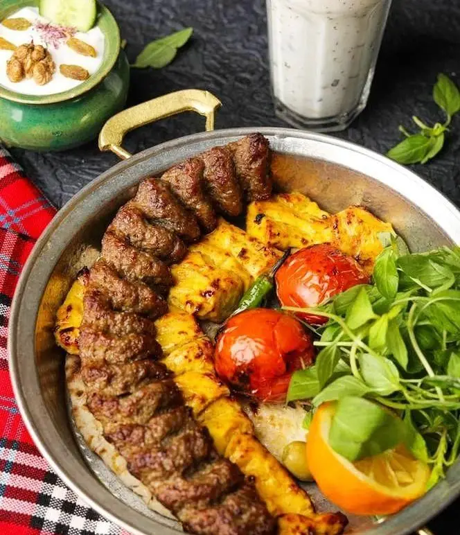 مجموعه کباب های لذیذ رستوران پیاله شامل کوبیده، جوجه، گوجه کبابی، سبزیجات تازه، همراه ماست و خیار و دوغ. غذای اصیل ایرانی.