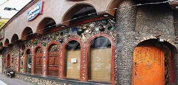 نمای بیرونی خاص رستوران پیاله با معماری سنتی، دیوارهای سنگی مزین به کاشی و سرامیک‌های رنگی، و درهای چوبی قدیمی با پنجره‌های طاق‌دار.