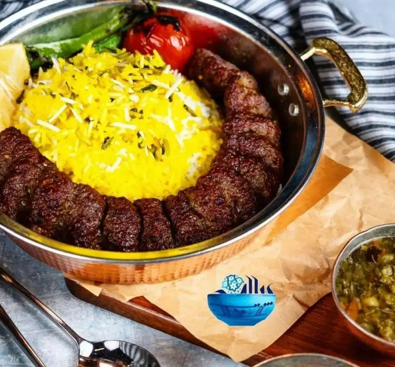 تصویری لذیذ از کباب کوبیده سنتی با برنج زعفرانی زرین، گوجه کبابی و لیمو تازه در سینی مسی از رستوران پیاله.