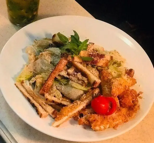 سالاد سزار با مرغ سوخاری ترد کافی شاپ تی شن، همراه کاهو تازه، نان کروتون، پنیر پارمزان و گوجه گیلاسی.