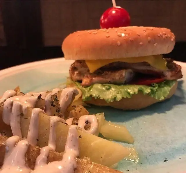 چیز برگر مرغ خوشمزه کافی شاپ تی شن با کاهو، پنیر و گوجه، در کنار سیب زمینی طعم دار و سس مخصوص و پاستا.