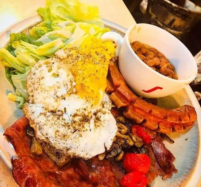 صبحانه مجلل کافه تی شن: تخم مرغ نیمرو، بیکن ترد، سوسیس گریل، سالاد سبز تازه، لوبیا و قارچ. انتخابی عالی برای برانچ.