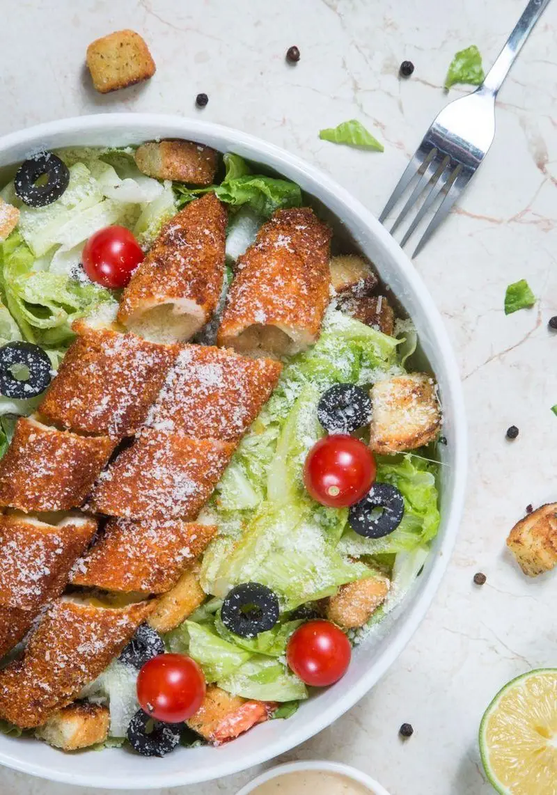 سالاد سزار مرغ سوخاری خوشمزه از سوخاری واویجه آهیل، با کاهو تازه، گوجه گیلاسی، زیتون، کروتون و پنیر پارمزان.