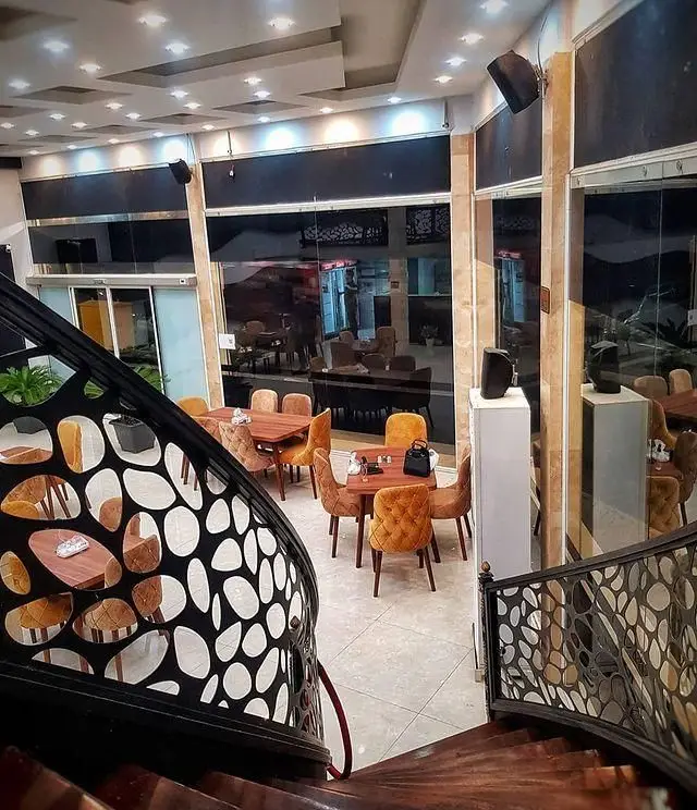 نمای داخلی رستوران آروند، با دکوراسیون شیک و مدرن، میز و صندلی‌های راحت برای مشتریان، راه پله‌ای زیبا و محیطی دلباز برای تجربه غذاخوری.