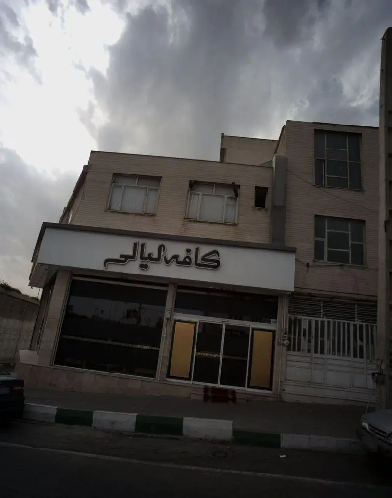 نمایی از ساختمان رستوران آروند با تابلوی کافه لیالی زیر آسمان ابری. ورودی شیشه‌ای و نمای زیبای کسب و کار در خیابان اصلی.